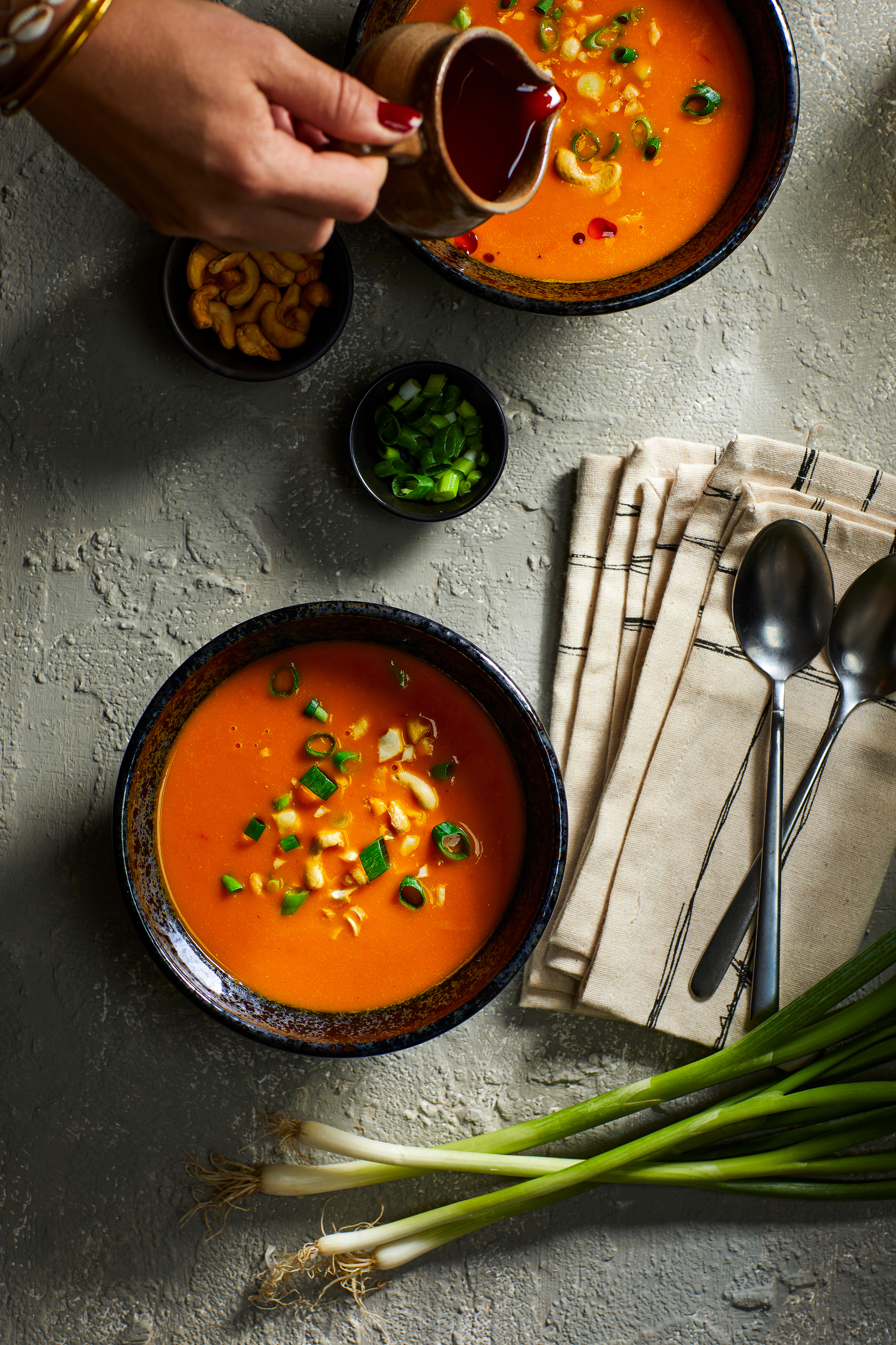 Lichte pompoensoep met tomaat, sambal-olie en cashewnoten