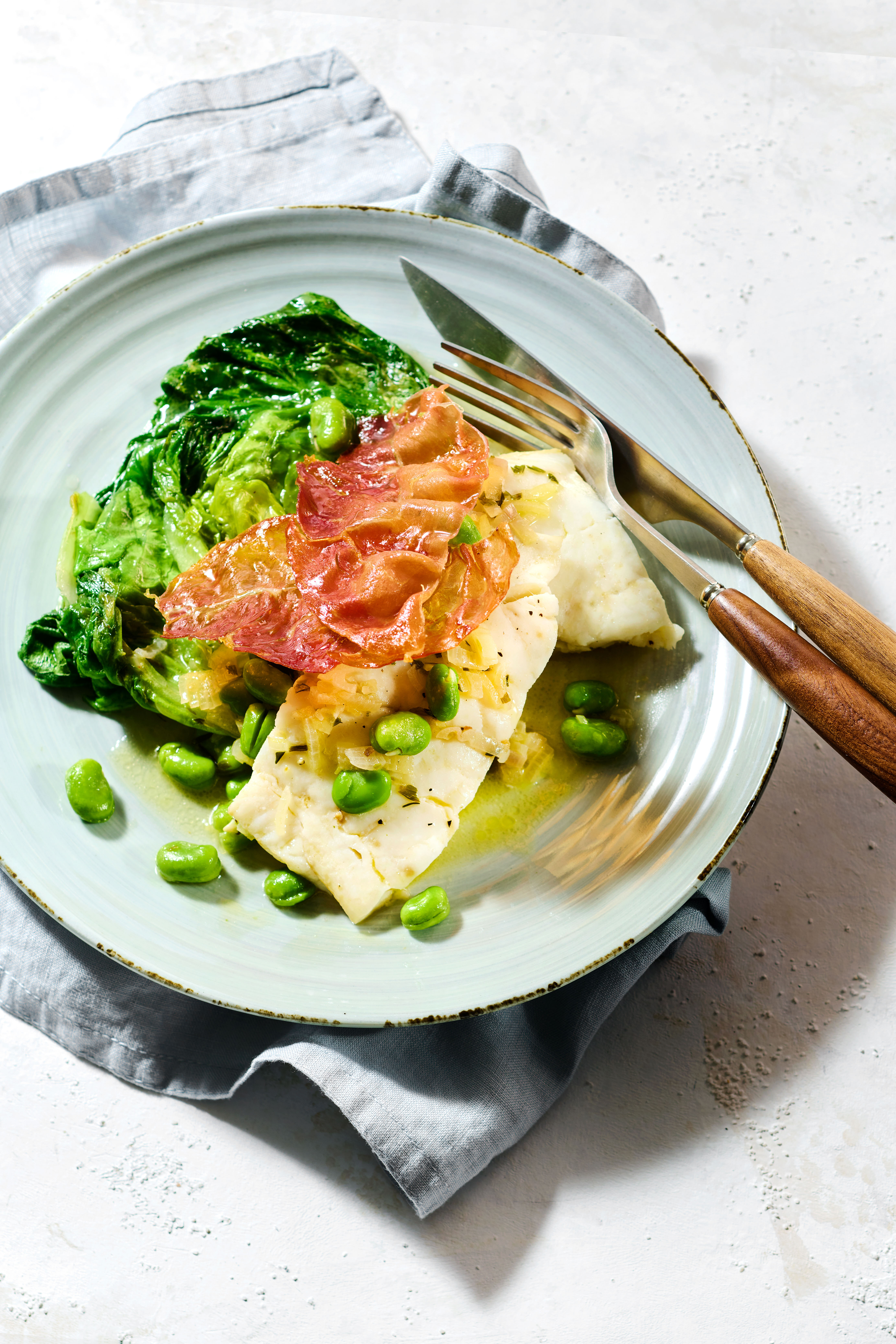 Gestoofde sla met tuinbonen, kabeljauw en krokante ham