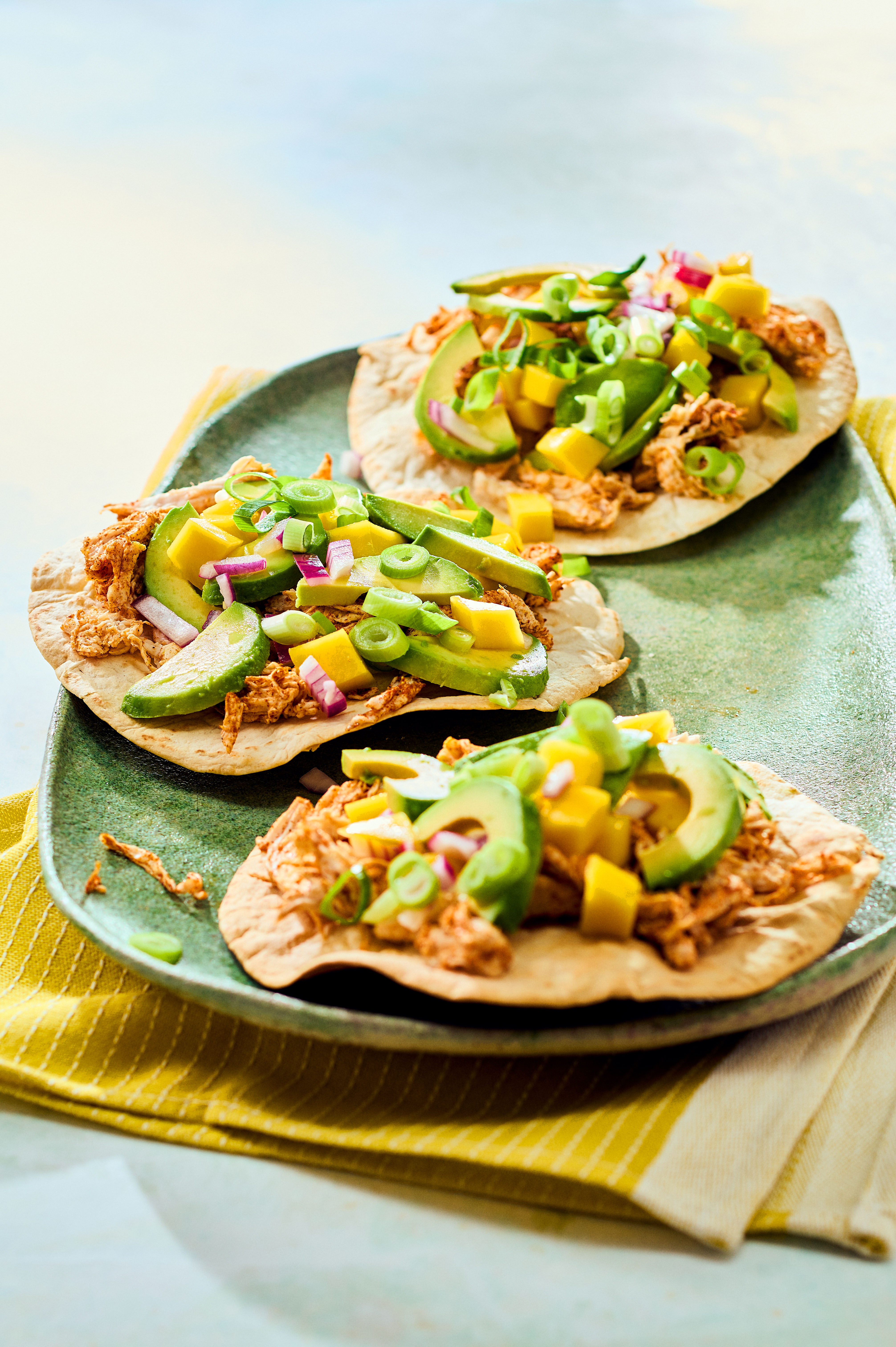 Tostada met pulled chicken, mango en avocado