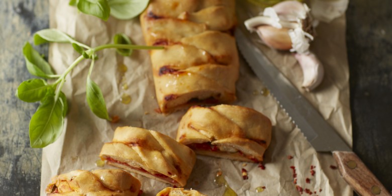 Gevlochten pizza met salami en gegrilde paprika